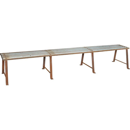 Lang solid bænk i rå metal og træ.